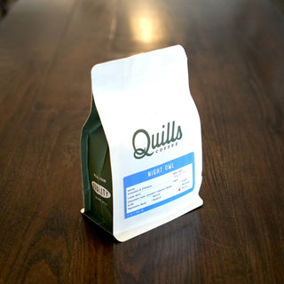 Close up of a white coffee bag label against a blurred background.