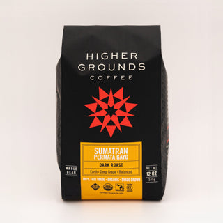 Sumatran Permata Gayo coffee bag from Higher Grounds on a wooden table with mint leaves, chocolate pieces, and coffee beans nearby.