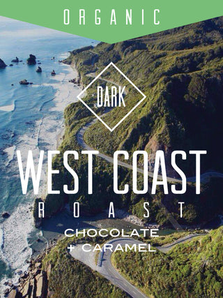 Front view of Organic West Coast Roast coffee bag with Dark roast diamond logo over a coastal cliff backdrop.