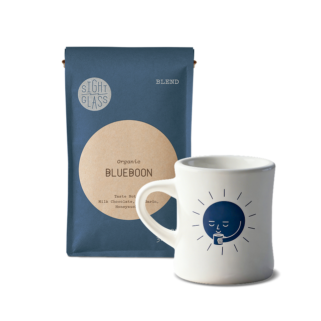 Blueboon organic coffee bag beside a white mug with a blue sun illustration