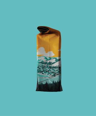 Partially opened Kayon Mountain Washed coffee bag with folded top against teal background