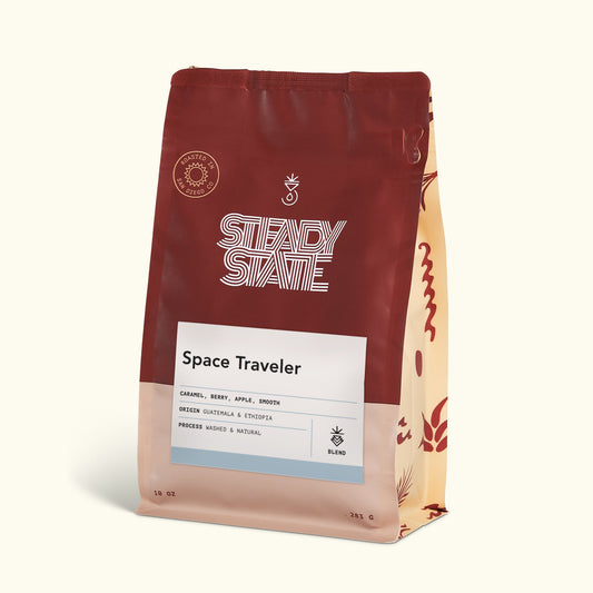 Space Traveler coffee bag in burgundy packaging with a white label and striped side panel.