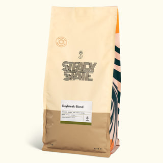 Daybreak Blend coffee bag in pale beige with a striped side panel and a label reading Daybreak Blend