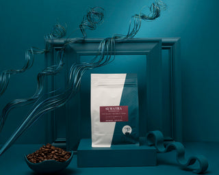 Sumatra Mandheling coffee bags arranged with a bowl of roasted coffee beans on a teal display