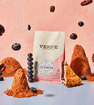 Sermon Espresso bag with pink diagonal panel surrounded by cocoa powder and pastries against a pink background.