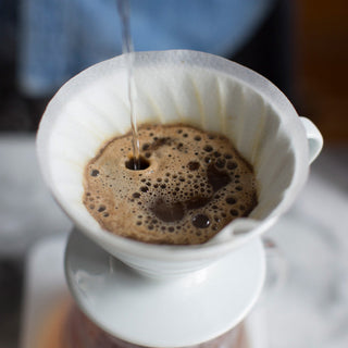 Pour over coffee brewing with a glass carafe and paper filter on a wooden table