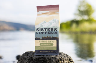 Sisters Blend coffee bag with mountain landscape artwork and bold Sisters Coffee branding.