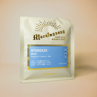 Angled white coffee bag showing a blue Stargaze Decaf label with gold border.