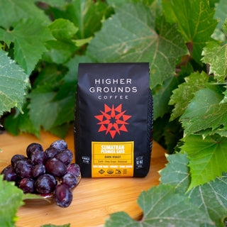 Sumatran Permata Gayo coffee bag from Higher Grounds nestled among green grapevine leaves.