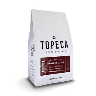 Corner view of a white Thunder Cloud coffee bag with a small logo on a plain background