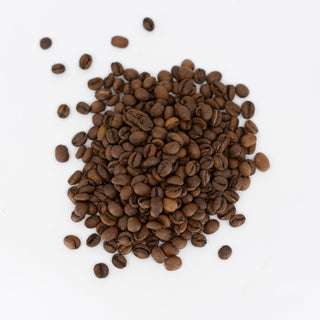 Pile of roasted Ethiopian Halo Beriti Natural coffee beans on a white surface