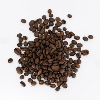 Scattered dark roasted coffee beans on a white background