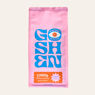 Close-up of a pink Ethiopia Yebesele Natural coffee bag with a blue logo on the front.