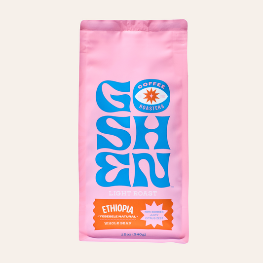 Close-up of a pink Ethiopia Yebesele Natural coffee bag with a blue logo on the front.