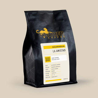 Black coffee bag with Panther Coffee logo in yellow and a white LA AMISTAD Nicaragua label