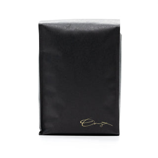 Black coffee bag shown from the side with a gold skull logo near the bottom