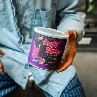 Person in a light denim shirt holding a Call Time coffee can with a purple pink illustrated label