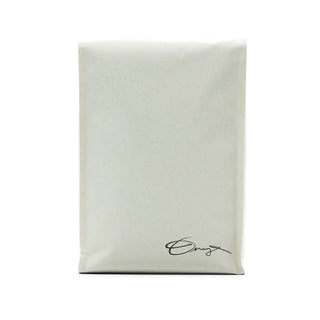 Cream kraft paper bag with a black handwritten signature at the bottom