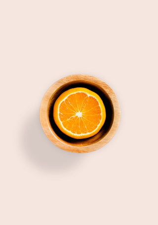 Orange half in a wooden bowl on a pale beige background