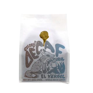 Decaf Colombia El Vergel Natural whole bean coffee bag with gold seal and whimsical artwork.