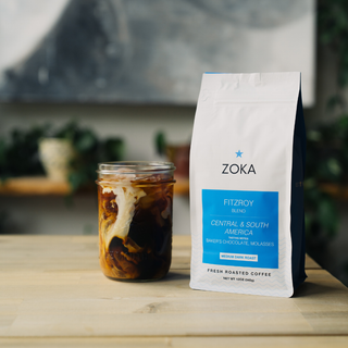 Front view of Zoka Fitzroy blend bag with blue label beside a glass of iced coffee