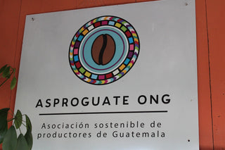 Signboard featuring a colorful circular coffee logo and Asociación sostenible de productores de Guatemala
