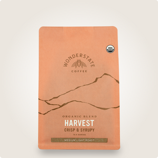 Orange coffee bag with USDA Organic seal and botanical illustration at the top
