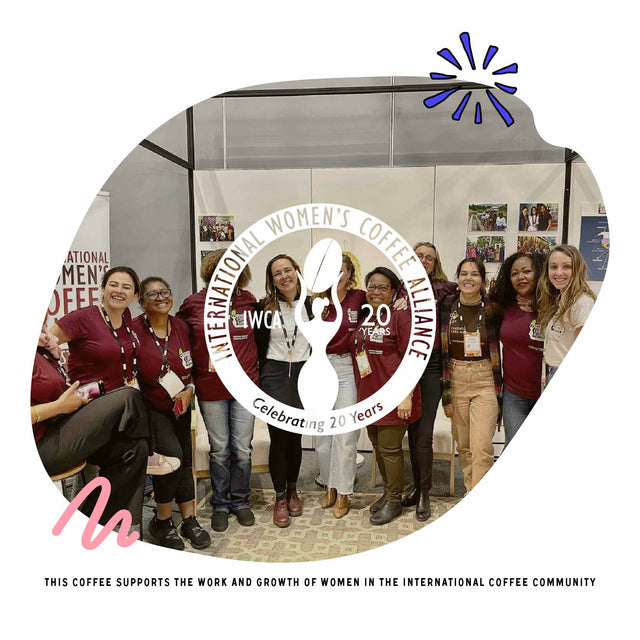 Group of women at an International Women's Coffee Alliance event with a large logo backdrop