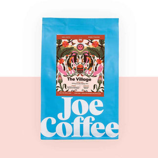 Bright blue Joe Coffee bag featuring The Village artwork on the label.