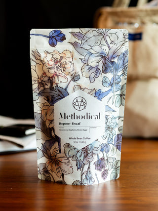 Repose Decaf coffee bag from Methodical Coffee featuring floral packaging and a white label.
