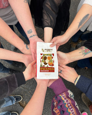 Group of hands around a Rwanda Agaseke Washed coffee bag