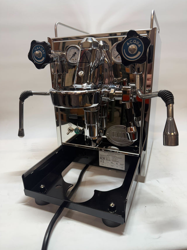 Close-up of a chrome ECM Mechanika Slim PID espresso machine with dual gauges and blue VAPORE and ACQUA knobs