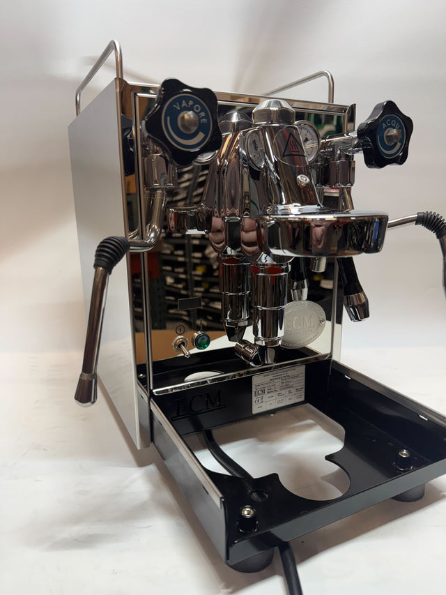 Angled view of the chrome ECM Mechanika Slim PID espresso machine with dual gauges and blue VAPORE and ACQUA knobs