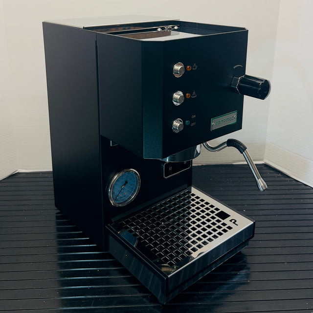 Open box Profitec GO espresso machine with two dials, pressure gauge, and portafilter handle.
