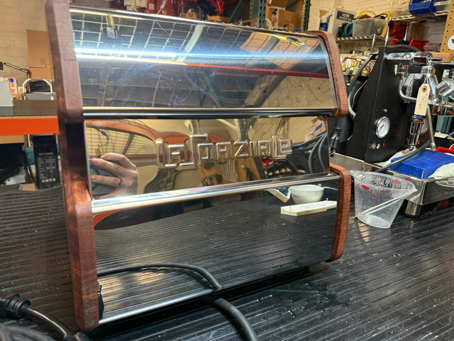 Side view of LUCCA A53 Mini Bubinga espresso machine showing a polished chrome panel and mounted group head.