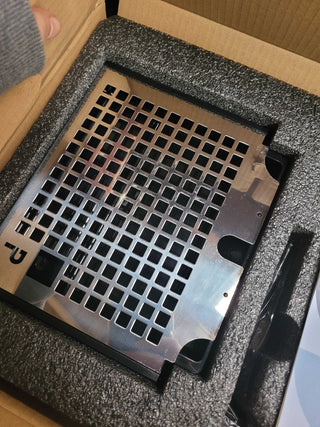 Close up of a stainless steel perforated grid panel on the Profitec GO with square openings and surrounding foam packaging