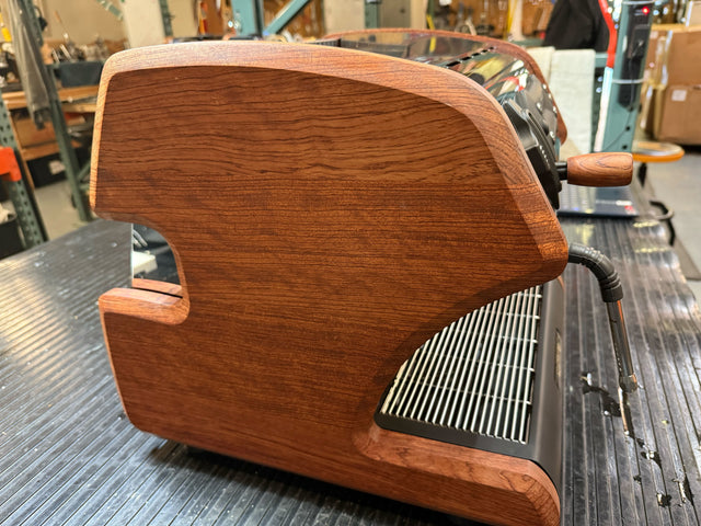Angled view of LUCCA A53 Mini Bubinga espresso machine showing chrome control panel and wooden side