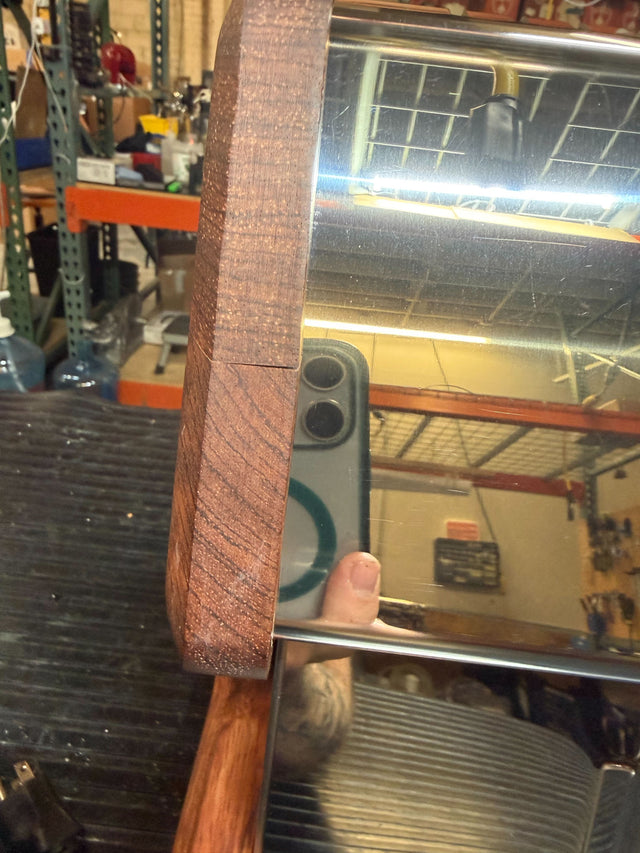 Close up of the Bubinga wood frame beside the reflective chrome surface on the LUCCA espresso machine.