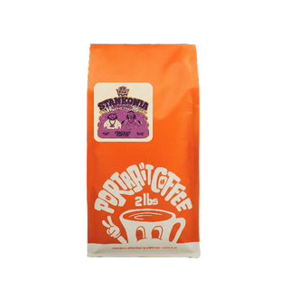 Bright orange Portrait Coffee Stankonia bag with a purple Stankonia label and a white coffee cup graphic.