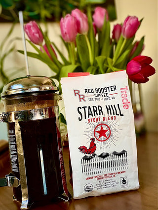 Starr Hill Stout Blend bag from Red Rooster Coffee beside a metal French press and pink tulips in the background