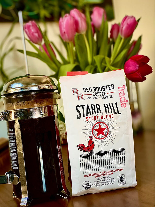 Starr Hill Stout Blend bag from Red Rooster Coffee beside a metal French press and pink tulips in the background