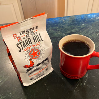 Starr Hill Stout Blend bag with a cup of black coffee in a red mug on a dark countertop