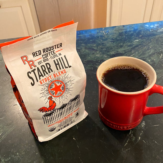 Starr Hill Stout Blend bag with a cup of black coffee in a red mug on a dark countertop
