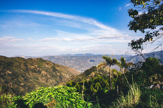 Panoramic view of green hills and distant mountains under a clear blue sky in Colombia's San Sebastián de La Plata region.