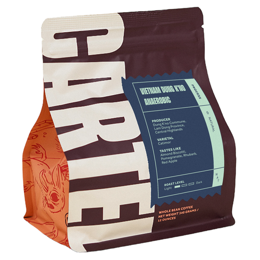 Coffee packaging with bold white graphic on a brown bag and a blue processing label