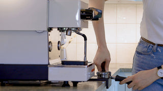 Barista hands secure a portafilter to an espresso machine during training.