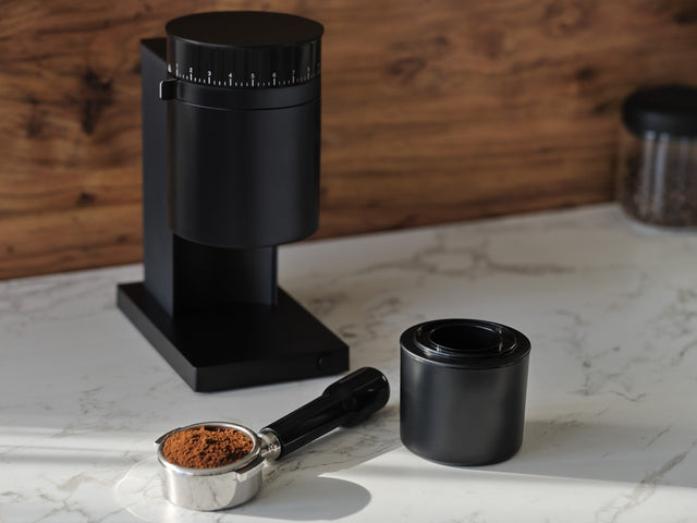 Fellow Opus Conical Burr Grinder, Matte Black, from Clive Coffee, portafilter and ground coffee, lifestyle