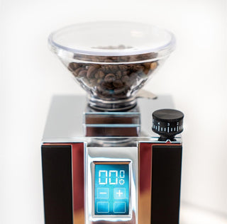 Clear coffee bean hopper atop a chrome Eureka Mignon single dose grinder with a blue digital display